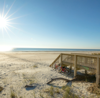 Stairs from a boardwalk lead to a sandy beach