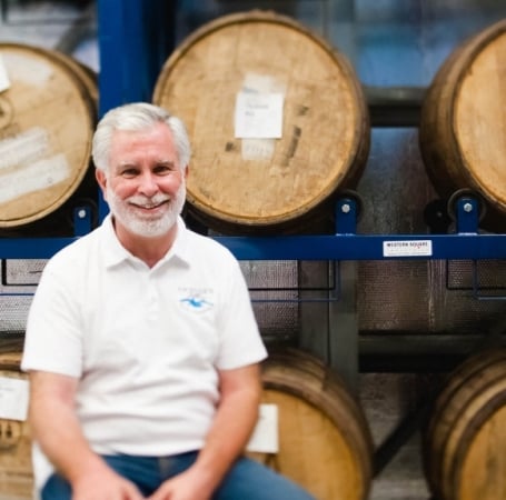 Man sitting infront of wine barrels