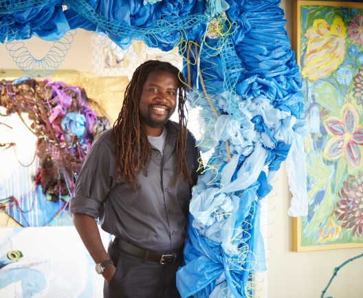 man standing displaying large blue art work 