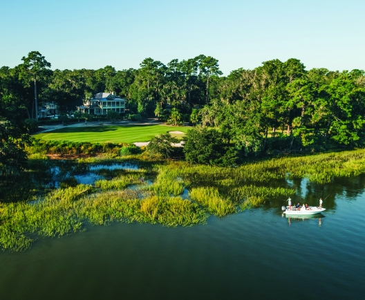 People fishing in a lake near a large house