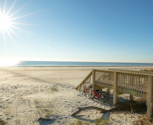Stairs from a boardwalk lead to a sandy beach