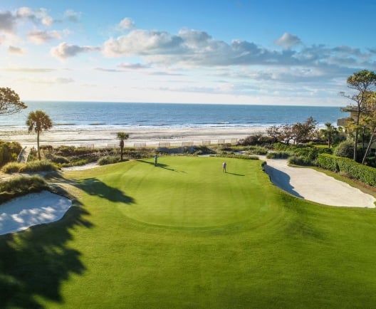Golfers on green by ocean