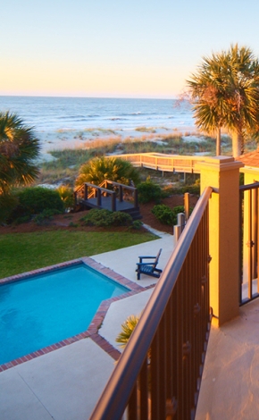 view from the balcony of a vacation home at sunset overlooking a private pool and the ocean