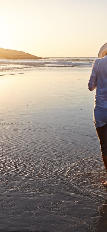 two people talking on a beach with their golden retriever dog at sunset