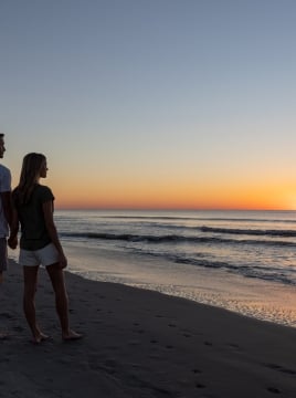 couple standing on the beach at sunrise