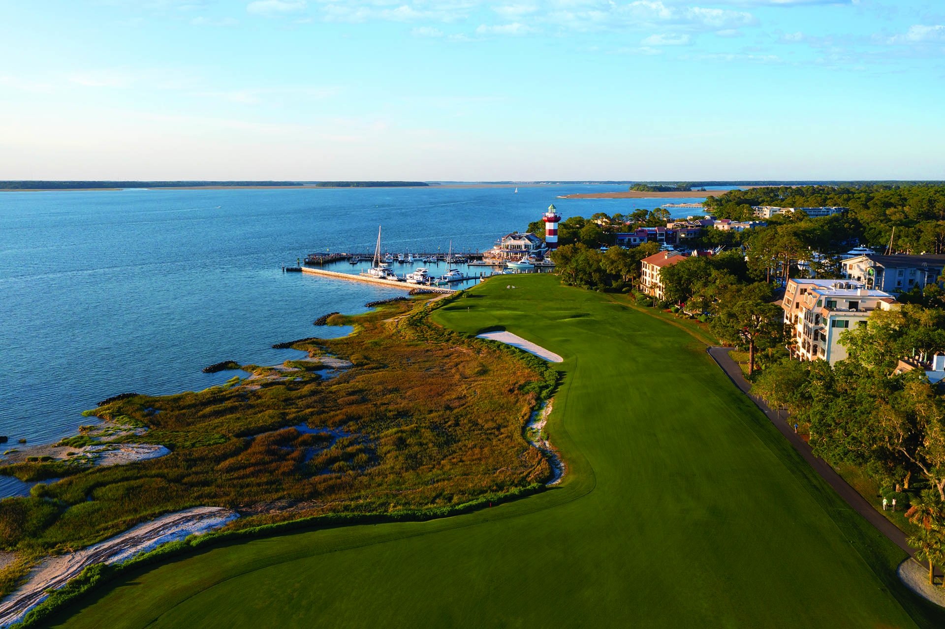aerial view of golf course with water and lighthouse in the background